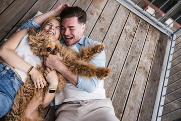 Happy young couple enjoying with dog on balcony