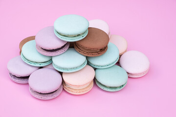 Different pastel colors pastry macarons on a pink background