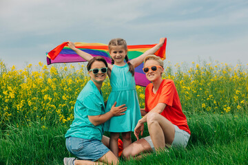 Happy lesbian mothers with daughter holding rainbow flag