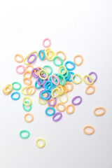 Many small multi-colored hair scrunchies on a pink pastel background