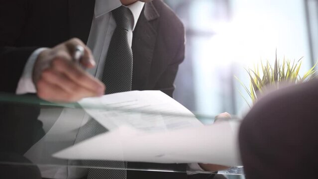 Businessman leafing through documents and signing contract for business deal at work in office closeup