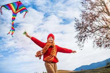 Small happy child runs and plays with kite in the autumn season. Blue sky with clouds background.