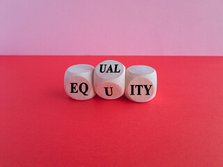 Equality or equity symbol. Turned a cube and changed the word 'equality' to 'equity'. Beautiful pink background, red table. Psychology, business and equality or equity concept. Copy space.