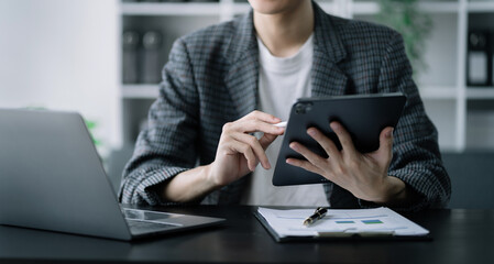 Businessman using a tablet to analysis graph company financial in office.
