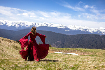 Fototapeta premium Woman dancing in the mountains. A beautiful view of the mountains. Red dress
