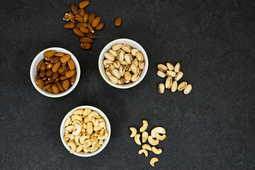 Obraz na płótnie Canvas nuts (almonds, pistachio, cashews) in bowls on grunge background 
