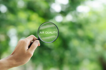 hand holding a magnifying glass to check the  good air quality and clean outdoor air quality safe...