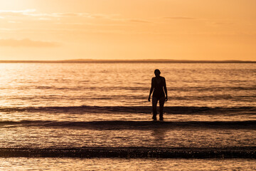 Fototapeta premium Silhouette of female swimmer going into the Atlantic ocean in Ireland