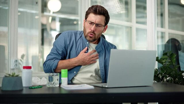 Trouble breathing, chest pain. Closeup of working bearded man in glasses, difficulty breathing or chest pain, touches his chest with hand. Heart attack, thoracic osteochondrosis, panic attack concept.
