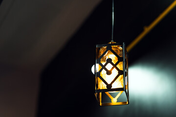 Square lamp with golden light hanging from the ceiling. Home decoration ideas.