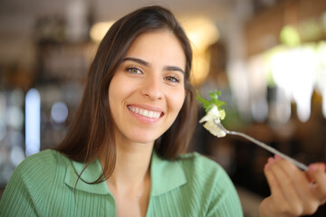 Happy woman holding fork with lettuce in a restaurant