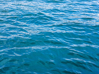 Obraz premium Blue green surface of the ocean with gentle ripples on the surface and light refracting. Natural background. The sea, the surface of the water. Close-up. Copy space