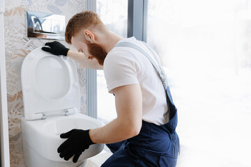 Professional plumber working with toilet bowl in bathroom. Concept install service plumbing