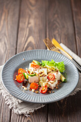 Feta cheese in cubes and vegetables - tomatoes and cucumbers in a plate. Light Greek salad with seedlings