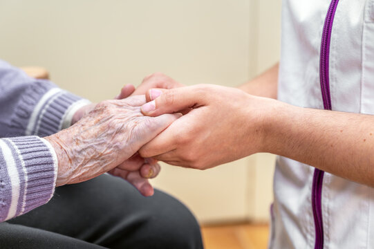 Close-up senior woman hand with her caregiver helping hands holding together, Caregiver visit at home. Home health care and nursing home concept. High quality photo