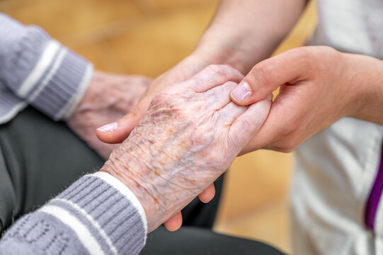 Close-up senior woman hand with her caregiver helping hands holding together, Caregiver visit at home. Home health care and nursing home concept. High quality photo
