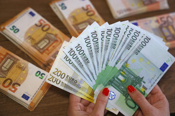 Euro cash money in female hands on the table. Close up of 200, 100 and 50 euro banknotes, concept of good earnings and shopping or business woman
