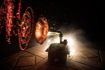 Music concept. Old gramophone on a dark background. Retro gramophone with disc on wooden table with toned backlight.