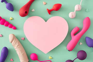 Erotic pleasure toy concepts for adults. Top view flat lay of colorful vibrators, dildo, anal plugs, vaginal balls, little hearts on turquoise background with blank heart for text or promo - obrazy, fototapety, plakaty