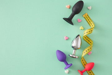 The impact of sex toy size theme. Top view flat lay of colorful anal plugs, tape measuring and...