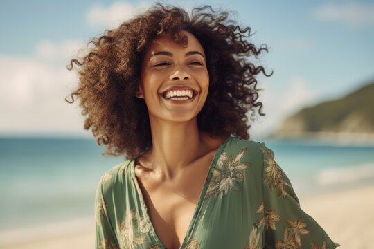 Close up portrait of a beautiful young african american woman with afro hairstyle smiling and looking away on the beach