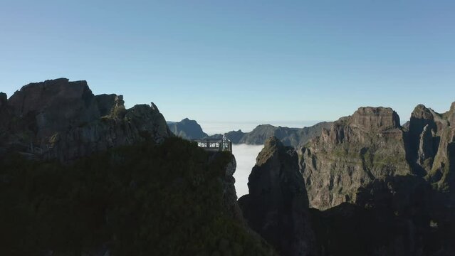 Woman standing on rock viewpoint high in Madeira mountains, aerial