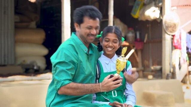 Shiksha, Beti bachao Beti padao. Importance of education - Indian village girl. The proud father beams with joy as his daughter triumphs and brings home the school cup. A moment of immense pride.
