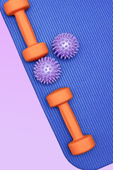 Vertical template with fitness massage balls and dumbbells on the soft sports mat. Workout concept with a copy space for text