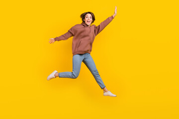 Full body photo of young model woman jump flying hands wear trendy sweatshirt have fun careless weekend isolated on yellow color background