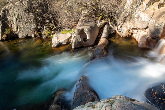 Fotografía del río de La Pedriza con una cascada y aguas cristalinas: La imagen muestra el río de La Pedriza fluyendo suavemente entre las rocas, con una hermosa cascada en el fondo.