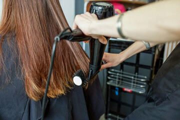 Fototapeta na wymiar Barber dries hair. Making hairstyle using hair dryer.