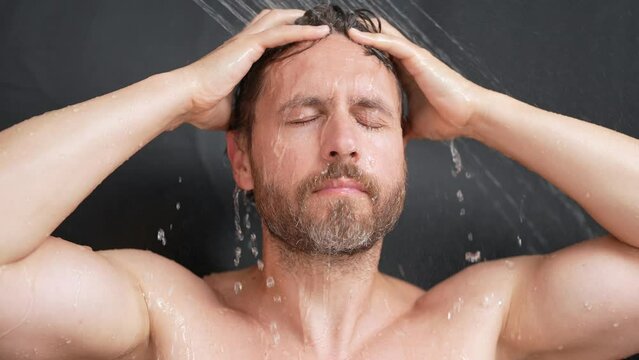 Portrait of man washing hair with shampoo taking shower. Washing hair with shampoo. Man washing hair with anti-dandruff shampoo, taking a shower. Hair care product, foam gel, shampoo and lotion.