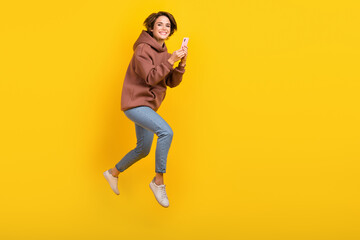 Fototapeta na wymiar Full body cadre of young running attractive girl hold phone bob hair blogging share instagram photo isolated on yellow color background