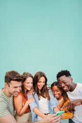 Vertical portrait of multiracial group of young friends smiling using their mobile phone app at...