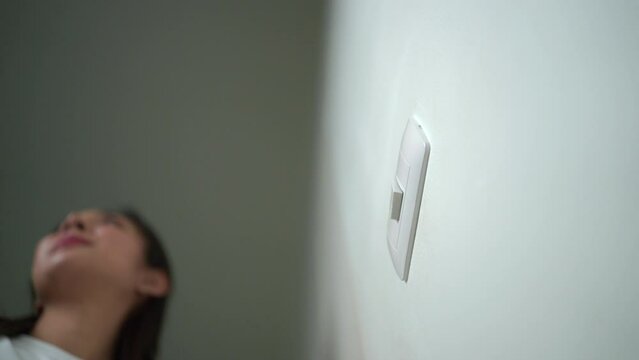 Earth Hour Close up woman finger turn off or on the light to saving electrical energy. Finger pushing light switch turn on or off. White switch.