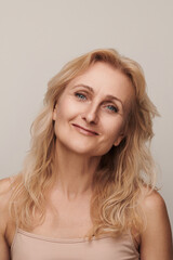 Beautiful blond middle aged woman smiling face looking camera portrait. Elegant mature lady no makeup 50 years old close-up isolated on white Women's health, cosmetology, skin care .