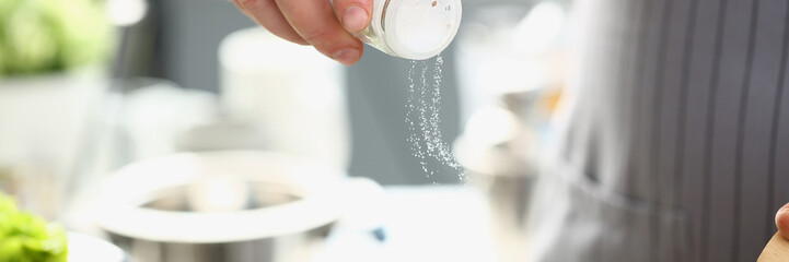 Chef adds salt from salt bowl to dish. Chef prepares a delicious dish