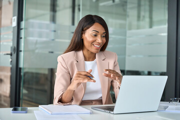 Obraz premium Happy professional young African American business woman hr manager team leader executive wearing suit working in office looking at laptop having video conference call virtual online meeting.