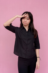 A stressed young woman unsure of what to do showing frustration at someone. Isolated on a pink background.