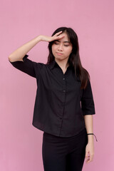 A stressed young woman unsure of what to do showing frustration at someone. Isolated on a pink...