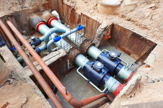 Pipe replacement. Installing PVC pipe conduit running through trench filled with dirt. Laying heating pipes in trench at construction site.