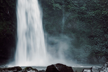 Waterfall with powerful flow in Bali, Indonesia. Tropical nature and epic Nungnung waterfall