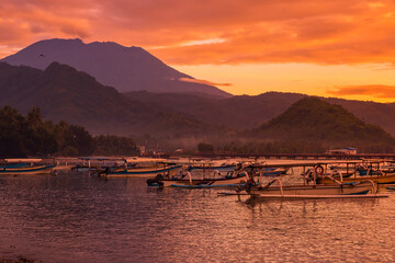 Sunrise with scenic landscape of Agung volcano and quiet ocean with local fishing boats