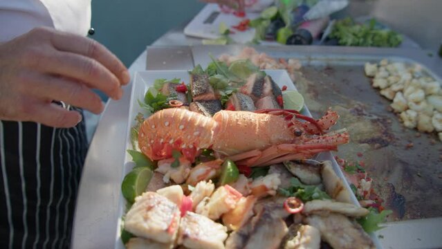 A chef puts the garnish on a gourmet seafood platter over a sizzling BBQ.