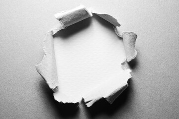 Black and white background of torn paper with hole