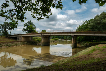 Fototapeta na wymiar Ponte sobre o rio num dia nublado com o reflexo da ponte sobre a água