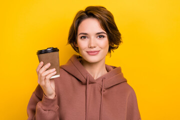 Portrait of pleasant cheerful cute girl dressed brown sportswear hold takeout cup of tasty coffee isolated on yellow color background
