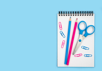 Flatlay composition with notebook, pencils and scissors on a blue background. Back to school....