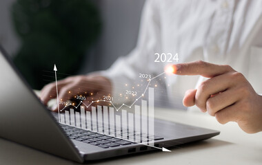 Businessman working on digital laptop computer with digital graph chart graphic, positive indicators in 2024, business calculate financial data, Digital marketing, finance, trade stock market concept.