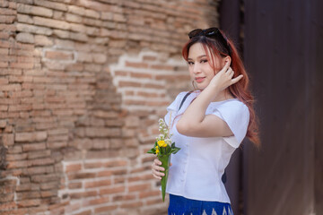 Pretty Asian tourists woman wearing beautiful hand-woven clothes dyed with indigo and mud-fermented natural colors modern Thai traditional dress costumes are popular in ancient temple Thailand.